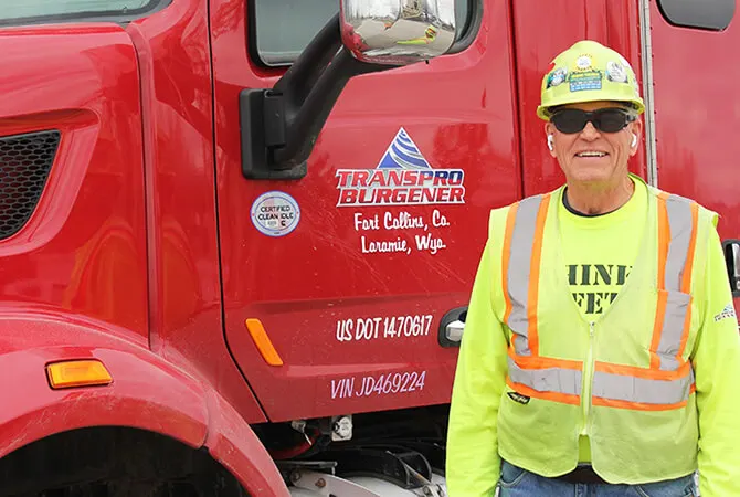 TransPro Burgener driver in a high-visibility vest beside a red truck cab