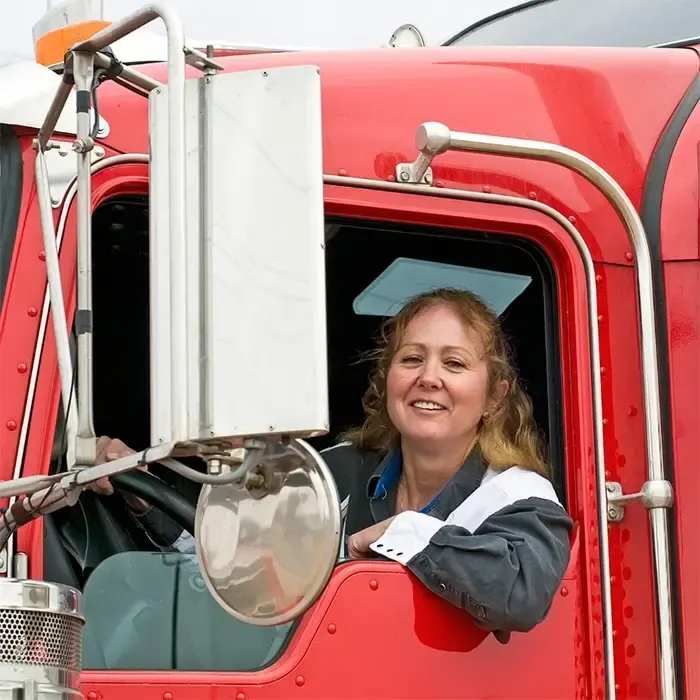 Smiling TransPro driver leaning out of a red Peterbilt cab