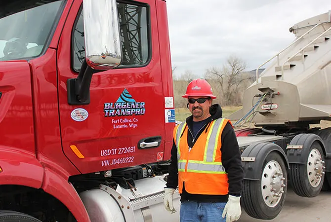 TransPro driver in a hard hat and safety vest beside his truck